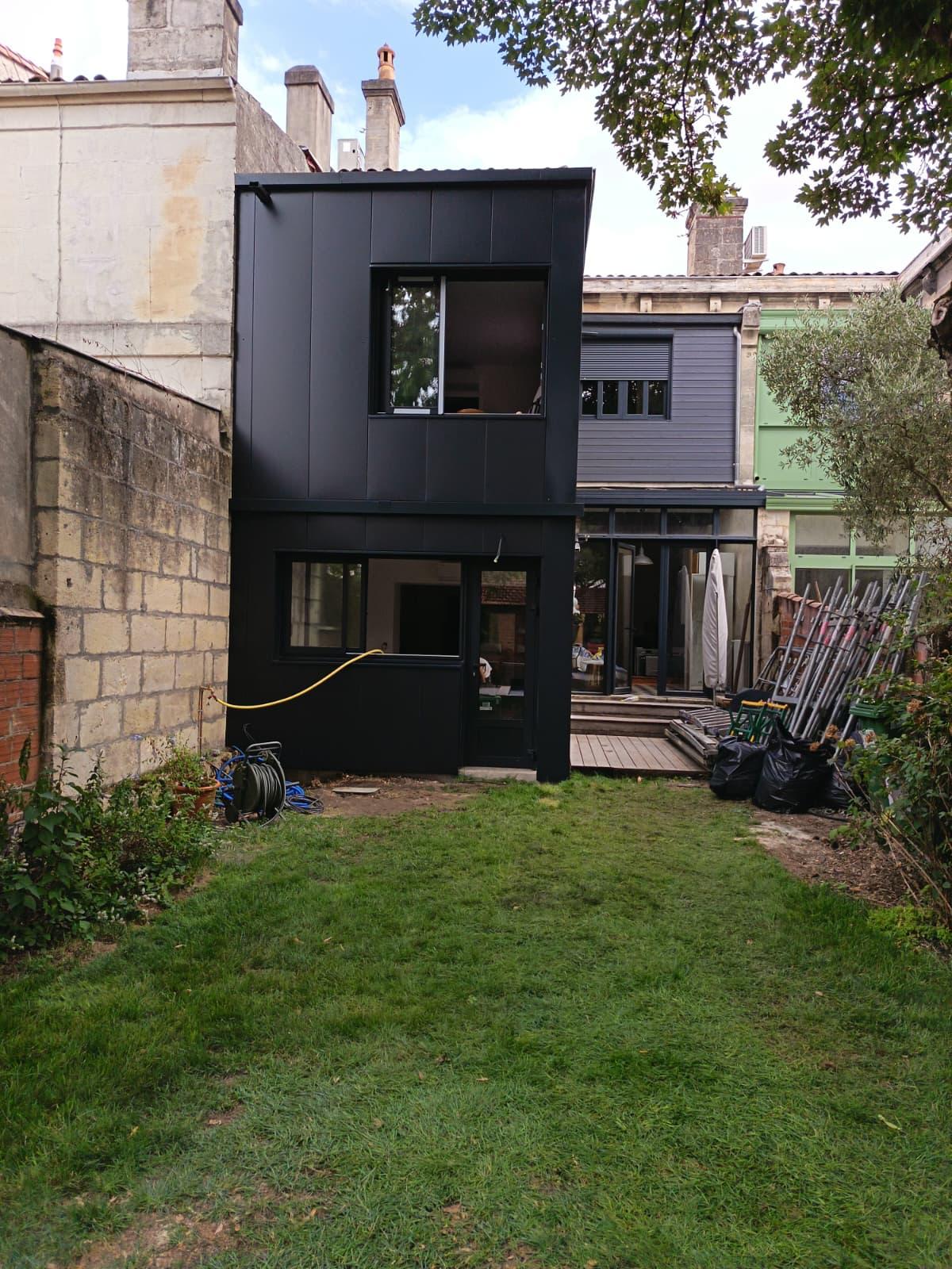 Extension en bois avec bardage noir greffée sur une maison de ville